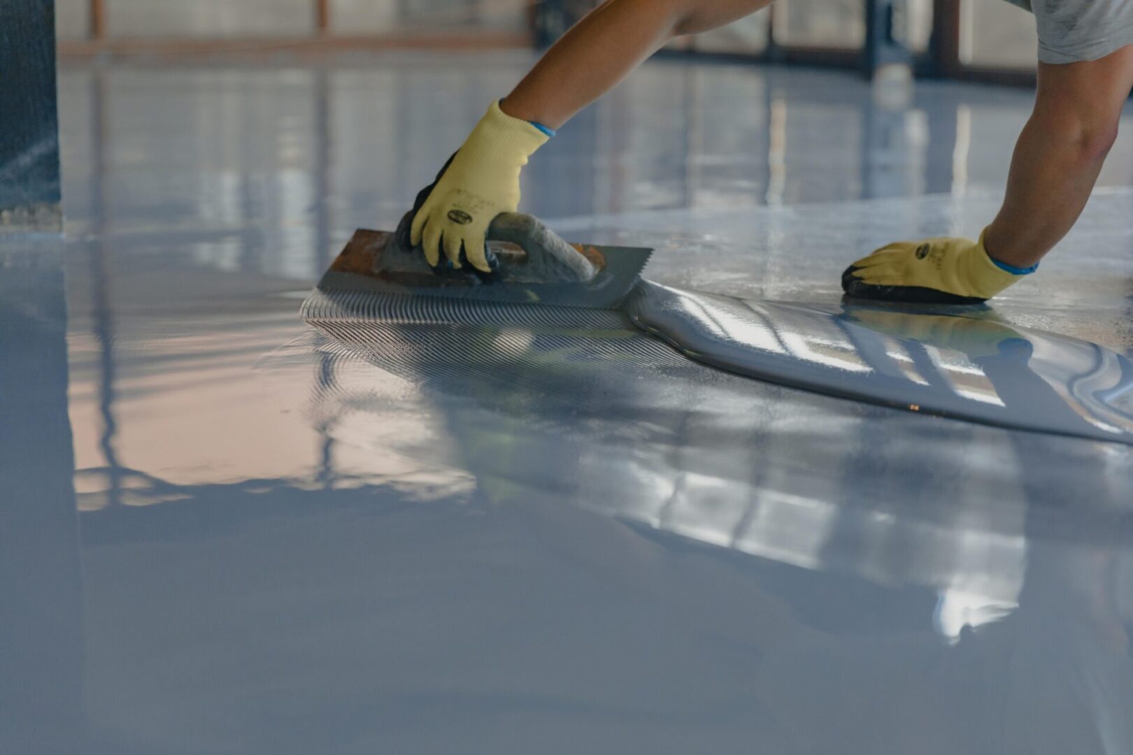 Worker smoothing epoxy floor coating.