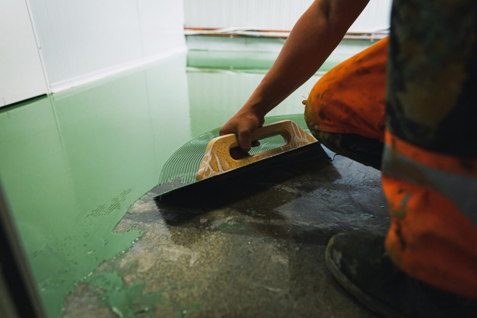 Worker smoothing green epoxy floor coating.