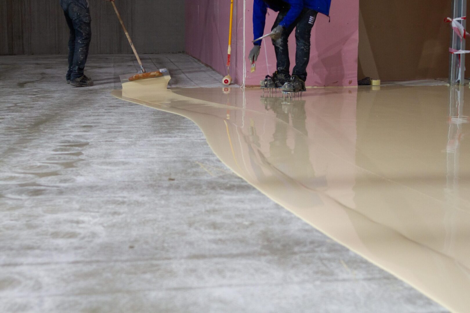 Workers pouring epoxy floor coating.