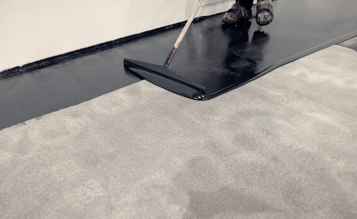 Applying black epoxy primer to concrete floor.